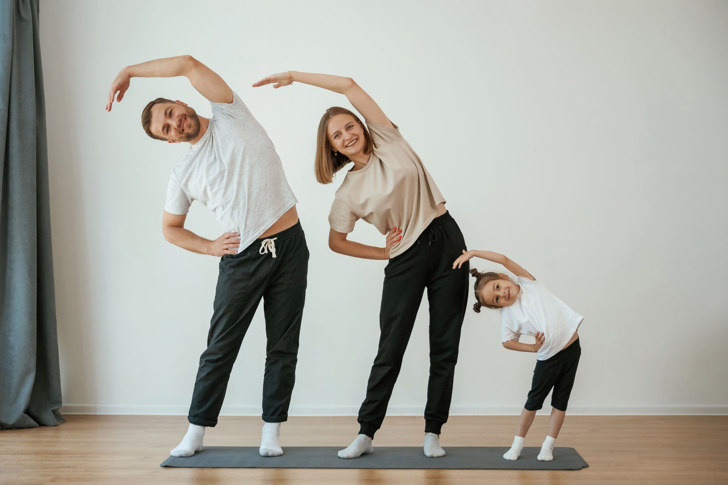 Family of four stretching together on a mat in a home setting